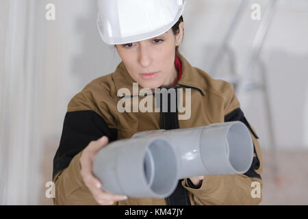 female builder checking a plastic pipes Stock Photo