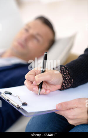 professional psychologist making notes on therapy session Stock Photo