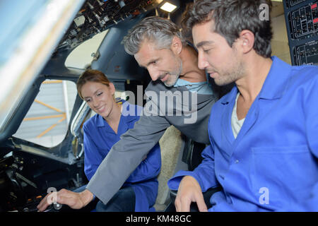 2 apprentices and teacher aero mechanics in aircraft cockpit Stock Photo