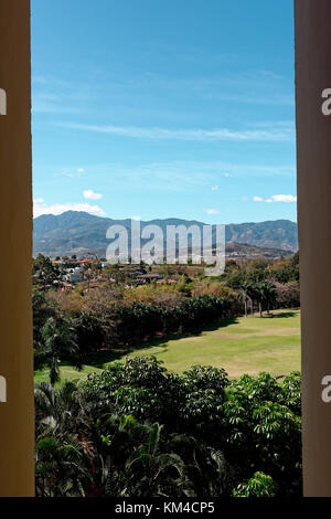 Cerros de Escazú mountain range viewed across golf course through a window Stock Photo