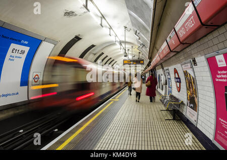 A train leaves Bond Street Station on the Central Line of the London Underground as passengers walk down the platform. Stock Photo