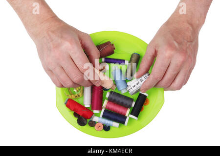 The old elderly tailor takes from the heap a spool of thread and a measuring tape. Isolated on white concept shot Stock Photo