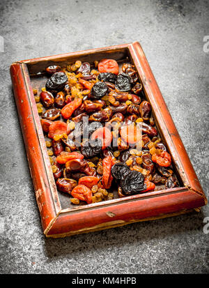 Various dried fruits in tray. On rustic background . Stock Photo