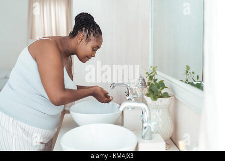 Young African woman washing her face in the morning Stock Photo