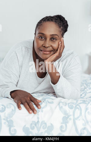Content African woman lying on her bed in the morning Stock Photo