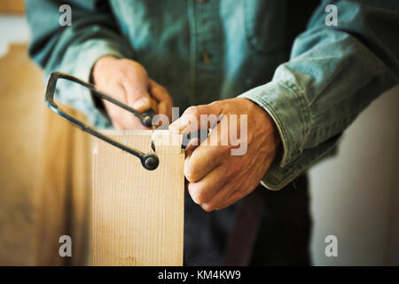 A man using a handsaw on a piece of wood. Stock Photo