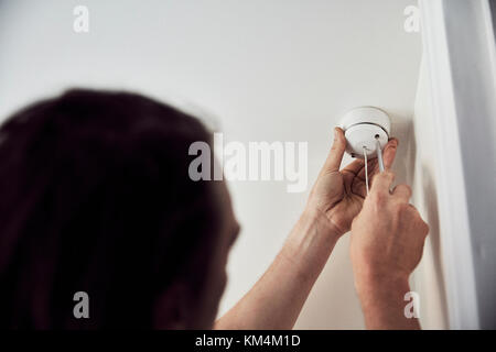 An electrician screwing the cap on a light fitting on the ceiling. Stock Photo