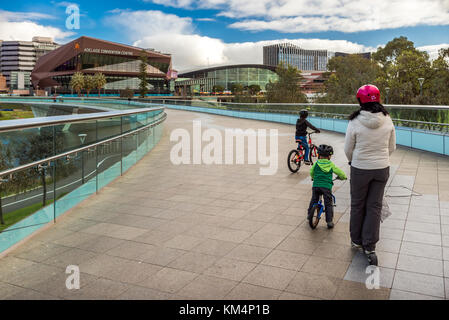 Adelaide, Australia - August 27, 2017: Mother with two sons ridind bicycles along Torrens footbridge in Adelaide city on a day Stock Photo