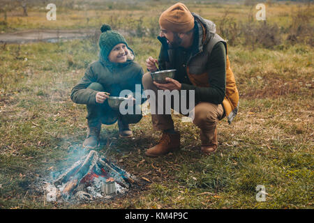 Father and son eating food on nature Stock Photo