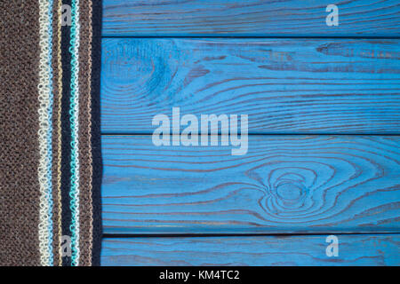 Fragment of a knitted scarf on blue wooden surface Stock Photo