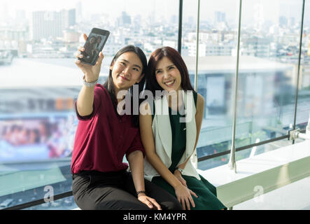 Couple Asian Women using the smartphone do selfie themself In the modern creative Office, business social network concept Stock Photo