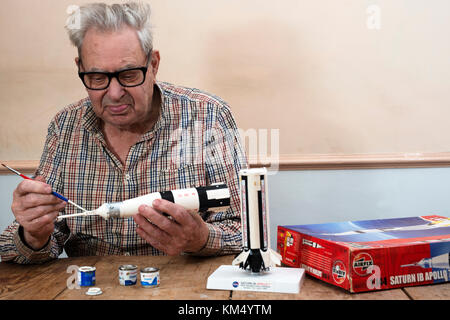 Elderly man making an Airfix plastic model Saturn Apollo 7 space rocket Stock Photo