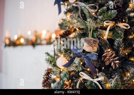 Christmas tree decorations. Toy knitted felt-boots and vintage bows and cones on cristmas tree. Close up shot Stock Photo