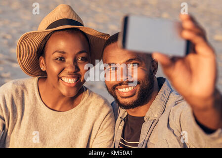 Content young African couple taking selfies together at the beach Stock Photo