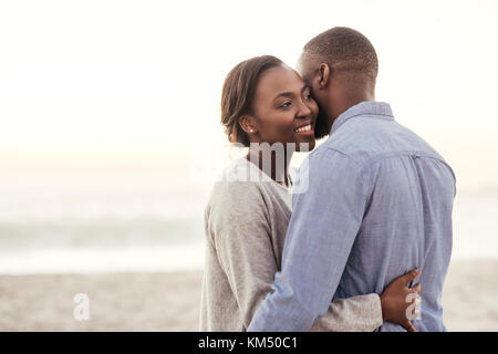 Young African woman embracing her husband at the beach Stock Photo