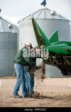 FARMER AND HELPER CLEAN A JOHN DEERE COMBINE BEFORE HEADING OUT TO HARVEST CORN IN UTICA, MINNESOTA. Stock Photo