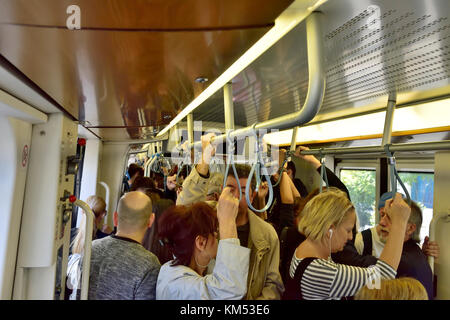 Inside crowded Athens tram with people standing holding on, Greece Stock Photo