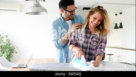 Young couple at home doing hosehold chores and ironing Stock Photo
