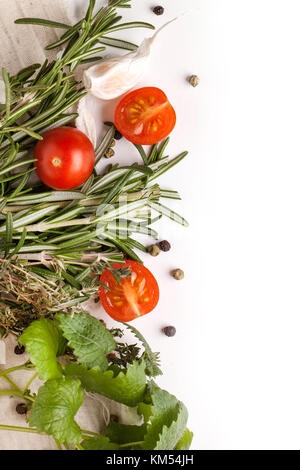 Top view on sliced tomatoes cherry with garlic and rosemary with thyme and melissa on white rag over white Stock Photo