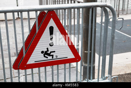 Caution wet floor; triangle warning sign mounted on steel street barriers Stock Photo