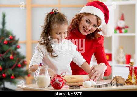 Adorable kid girl and mother baking Christmas cookies Stock Photo