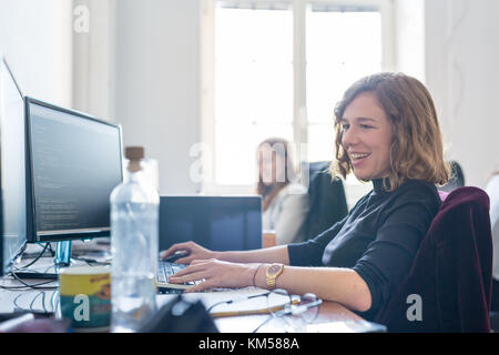 Yound devoted female software developers team working on desktop computer in IT statup company. Stock Photo