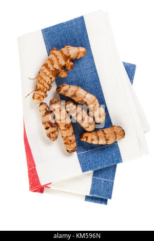 Turmeric rhizomes on striped kitchen towel, from above, isolated on white background Stock Photo