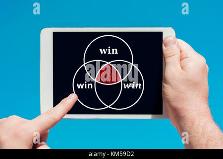 Man holding a tablet device showing a partnership and cooperation symbol in blue sky background. Stock Photo