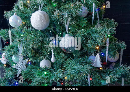 Closeup of white baubles and decorations with colored lights on an xmas tree Stock Photo