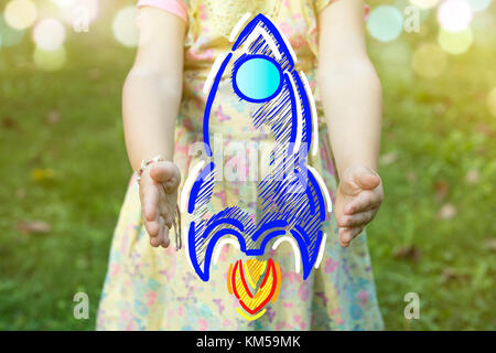 Child holding a rocket drawing as startup concept outdoors on a sunny day. Stock Photo