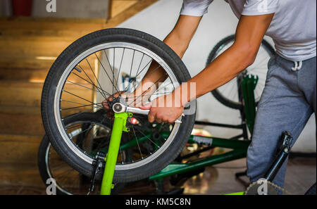 Close up of bicycle mechanic in a workshop in the repair process of the wheel with a wrench Stock Photo