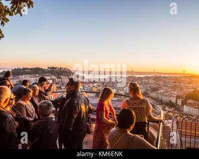 LISBON, PORTUGAL - NOVEMBER 19, 2017: Tourists at Belvedere of Our Lady of the Hill viewpoint, looking at the cityscape of Lisbon at sunset. Stock Photo