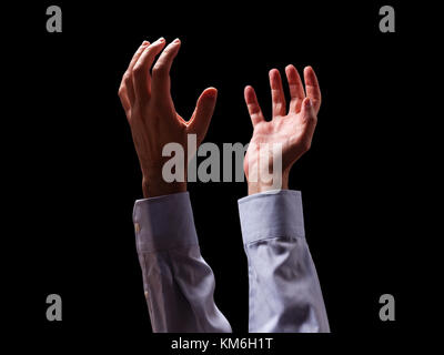 Male arms and hands raised and outstretched in the air to god. Man praying begging pleading imploring or supplicating. Black background. Businessman Stock Photo