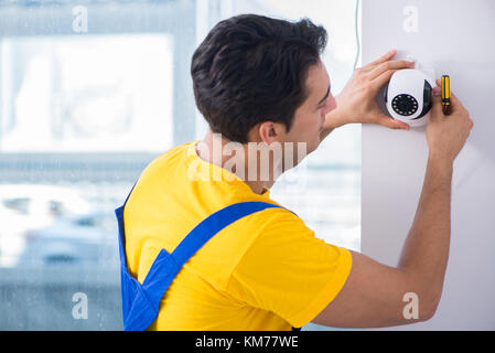 Contractor installing surveillance CCTV cameras in office Stock Photo
