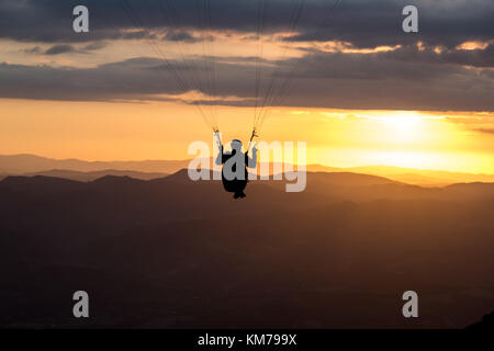 A paraglider silhouette flying against the sunset over Mt.Cucco (Umbria, Italy) Stock Photo