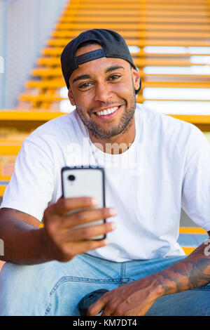 Portrait of a young man sitting on stairs using smartphone Stock Photo