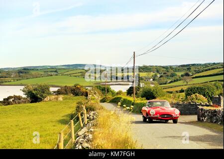 Strangford Lough at Killinchy, Co. Down, Northern Ireland. E-type Jaguar motorcar driving on country lane. Stock Photo