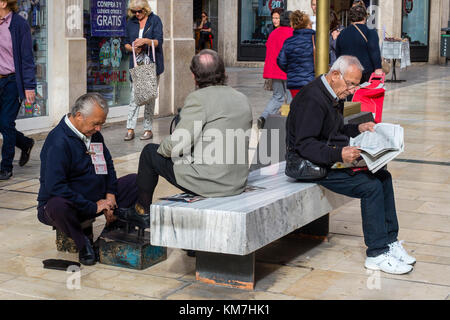 Man having his shoes shined on the street, in Malaga, Spain Stock Photo