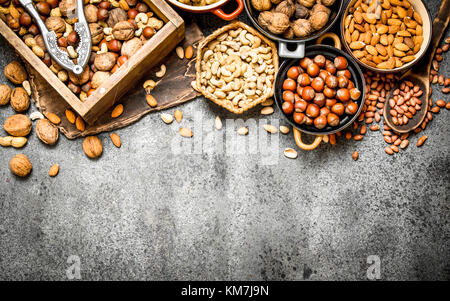 Many different nuts in the box and bowls. On rustic background. Stock Photo
