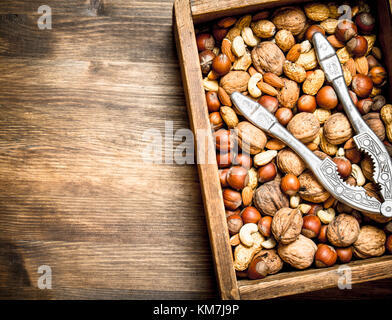 Different nuts with the Nutcracker in the old box. On a wooden table. Stock Photo