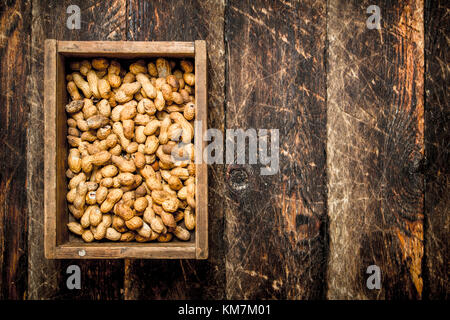 Peanuts in an old box. On wooden background. Stock Photo