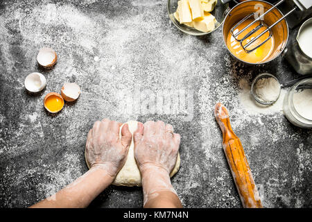 Dough background. Woman kneads dough with various ingredients on the table. On rustic background . Stock Photo