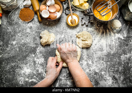 Dough background. Woman kneads dough with various ingredients on the table. On rustic background . Stock Photo