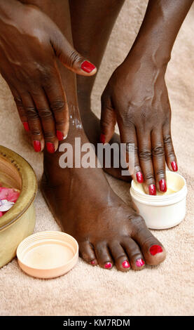 African woman rubbing cream on herself Stock Photo