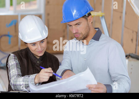 cheerful coleagues reviewing documents together at site Stock Photo
