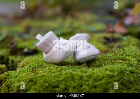 Little pink baby slippers on green grass background. Baby shoes Stock Photo