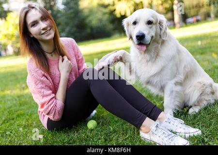 Photo of brunette with ball and dog sitting on lawn Stock Photo
