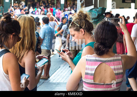 Seattle, Washington, USA - September 4th, 2017: Four young women are chatting and taking photos with their mobiles at the Pike Public Market in Seattl Stock Photo