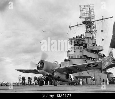 A Grumman F4F-4 Wildcat fighter taking off from USS Ranger (CV-4) to attack targets ashore during the invasion of Morocco, circa 8 November 1942. Note: Army observation planes in the left middle distance; Loudspeakers and radar antenna on Ranger's mast. Operation Torch Stock Photo