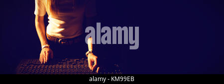 Mid section of female DJ operating sound mixer at nightclub Stock Photo